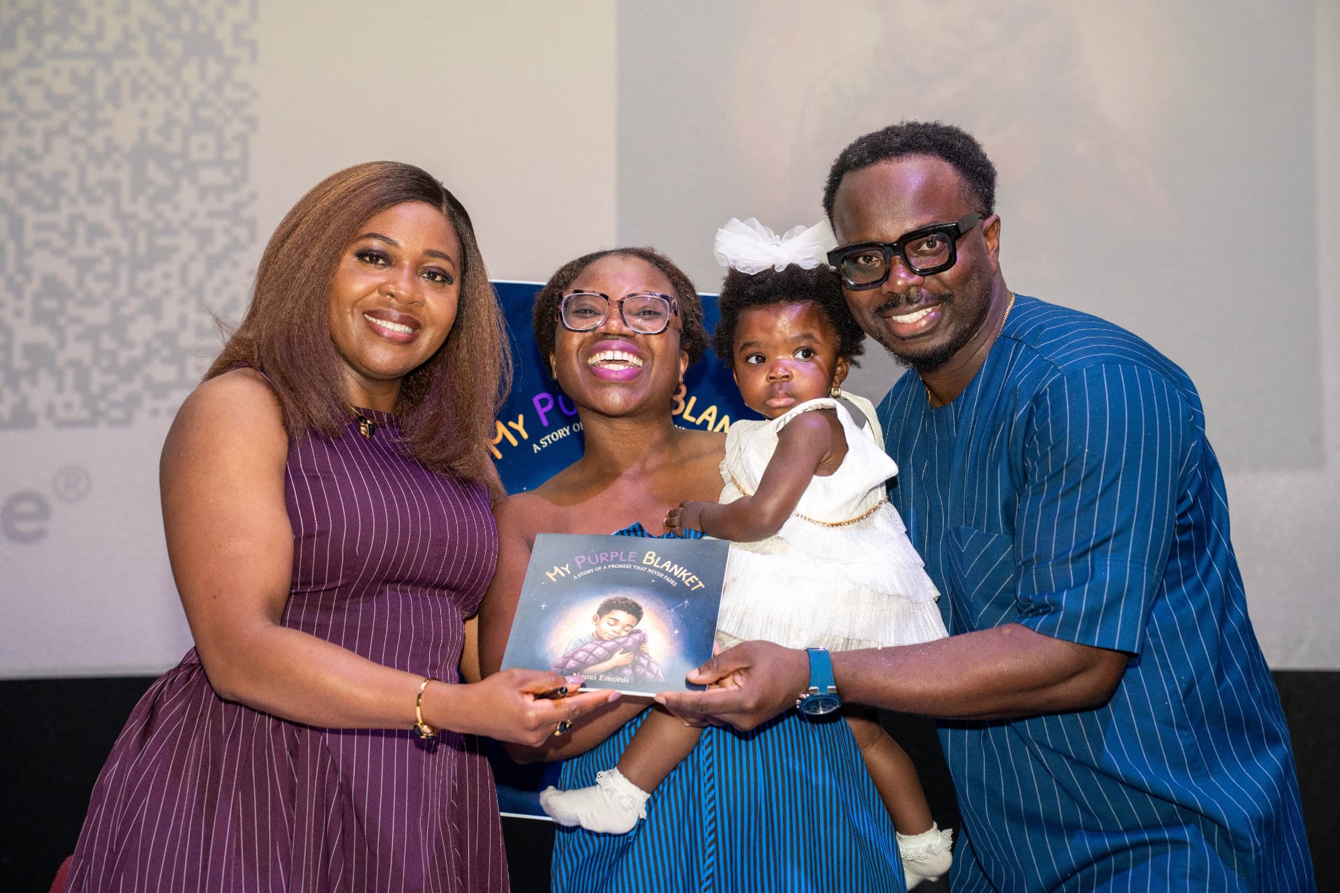 Ngozi with a family and their young child holding the book